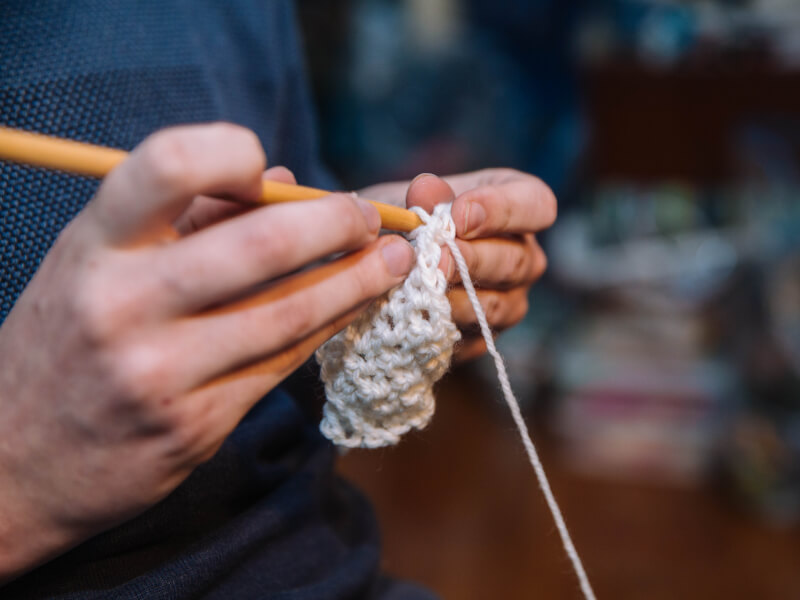 Close-up of someone's hands knitting with white wool